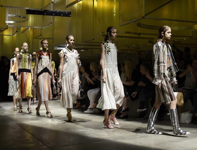 MIUCCIA PRADA RIVOLUZIONA IL TAILLEUR - Nel secondo giorno di sfilate Prada, in via Fogazzaro, osa e convince la critica. Protagonista della collezione primavera estate 2016 è senz'altro il tailleur: rivisto e corretto, stravolto e ricomposto. Quella andata in scena ieri è sicuramente, finora, una delle migliori passerelle che si sono viste in questa Fashion Week. Miuccia non sbaglia un colpo e ancora una volta si impone con il suo stile. Il duo giacca-gonna viene scomposto e ricomposto con fantasie a righe, colletti reverse, gonne con sovrapposizioni di tessuti e lunghezze diverse. Per quanto riguarda gli accessori, punto forte del brand, meritano un plauso particolare le borse, bauletti e tracolline dove si sposano perfettamente stampe pitonate e righe.