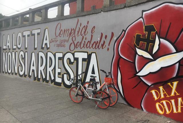 "La lotta non si arresta - Complici e solidali contro carcere e capitale". Non è stato ancora rimosso il mega murale in onore di Dax in Darsena: come ogni anno, nell'anniversario del suo assassinio per mano dei fratelli Federico e Mattia Morbi e del padre Giorgio, il coordinamento Memoria Antifascista ed il centro sociali di Milano sfilano il 16 marzo. E come ogni anno viene realizzato in Darsena un murale in ricordo di Davide Cesare, morto nel 2003 dopo l'aggressione all'esterno di un bar in via Brioschi. L'anno scorso la cancellazione dei murales era avvenuta a pochi giorni di distanza dalla loro comparsa. (foto: Claudio Bernieri)
