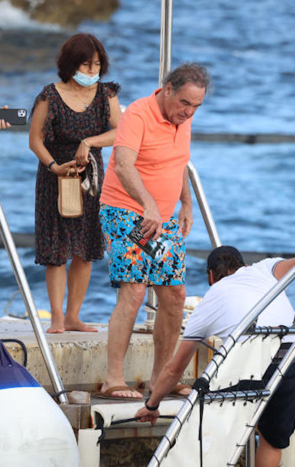 Antibes, Oliver Stone in costume a fiori e infradito cerca di salire in barca