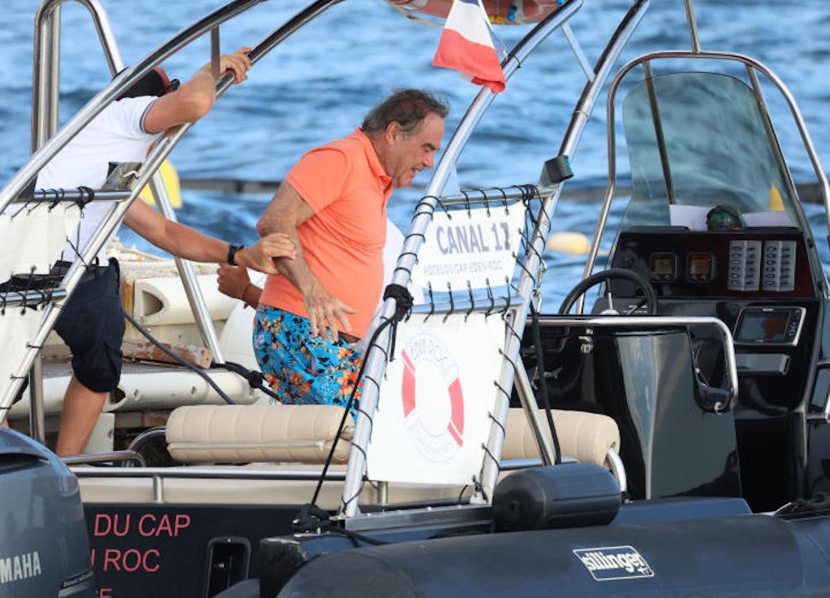 Antibes, Oliver Stone in costume a fiori e infradito cerca di salire in barca