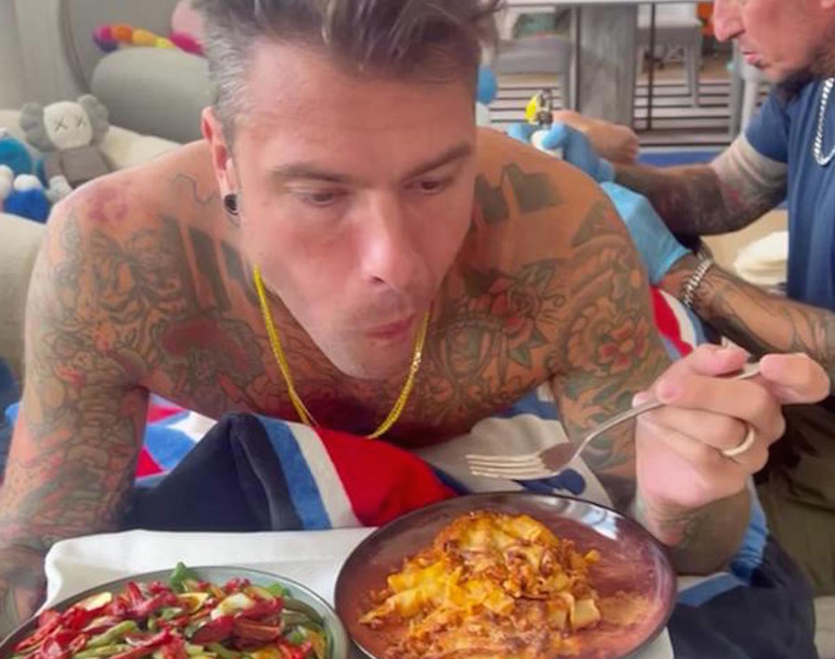 Fedez mentre si tatua la schiena, il sedere e la gamba mangia lasagne