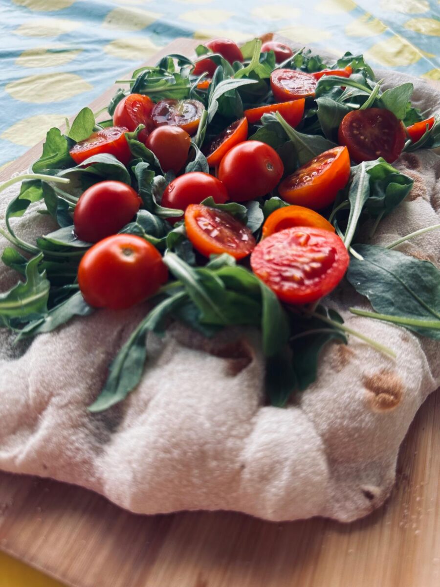 Pinsa romana, l’antica arte del “pinsere” rivive in una teglia di rucola e pomodorini – VIDEO